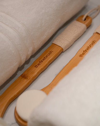 Bamboo shower brush resting on linen — ultra-soft bristles for gentle daily exfoliation and skin barrier care