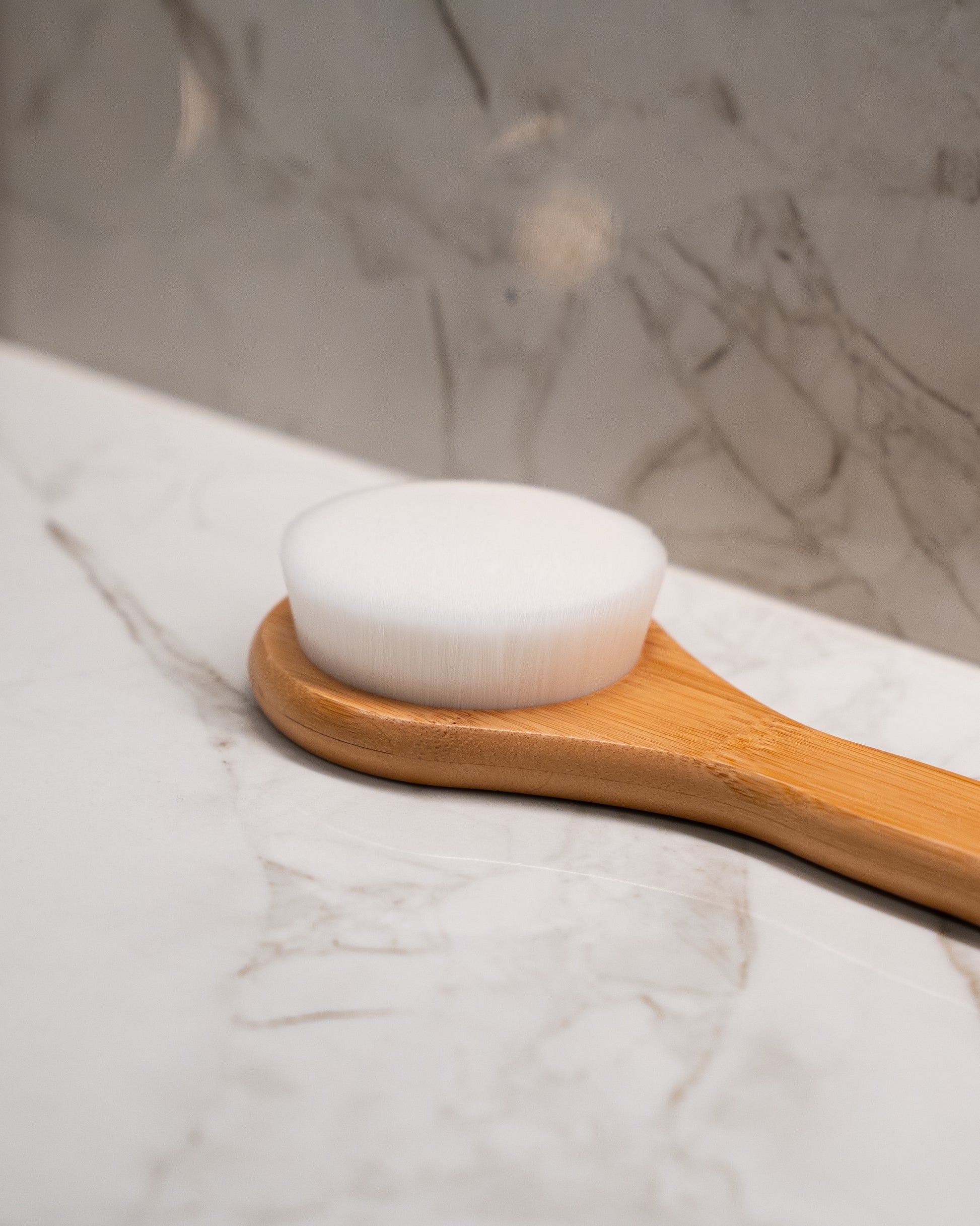 Bamboo body brush angled shot — gentle exfoliating shower brush designed to protect the skin barrier